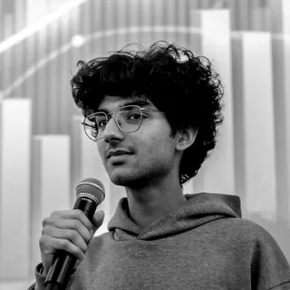 Aryav Saigal holding a microphone in a black-and-white portrait