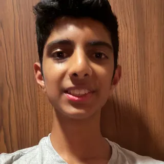 Ashwin Rajan smiling in front of a wood-paneled wall