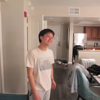 Guy Sreesangkom laughing in a cream t-shirt