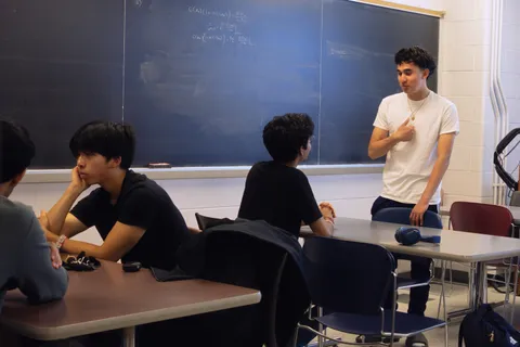 A SIGecom member explaining a concept at the blackboard to fellow members