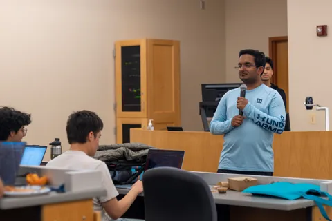 A SIGecom member speaking into a microphone while presenting to seated members