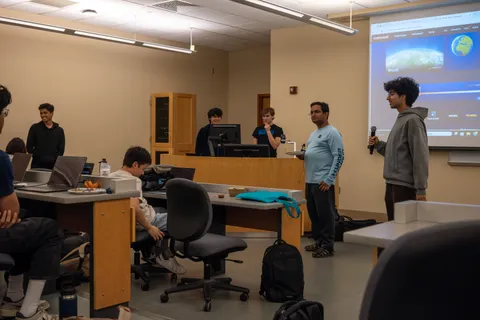 A SIGecom member presenting to the group with a GeoGuessr map on the projector screen