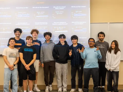 SIGecom members posing together in front of a Predictions Lab presentation slide